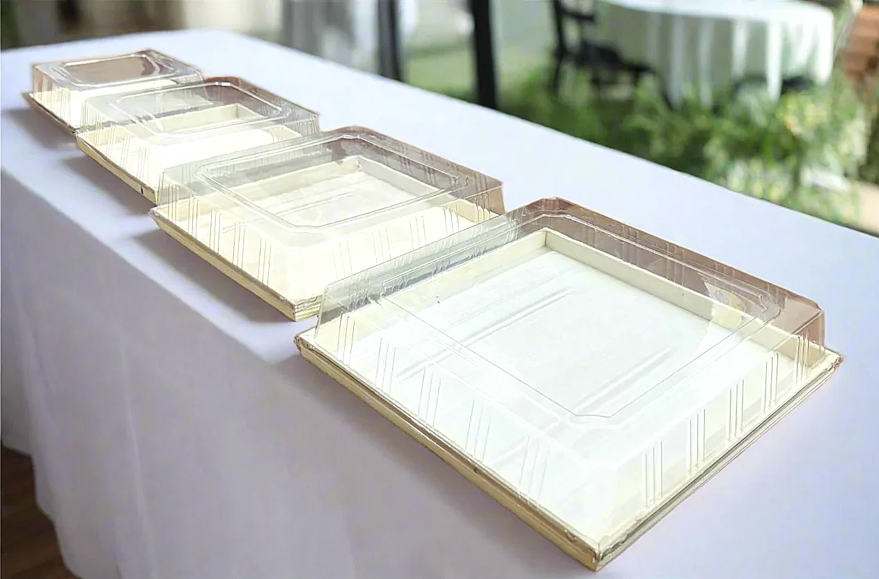 Set of clear plastic trays on a white tablecloth with a blurred outdoor background

