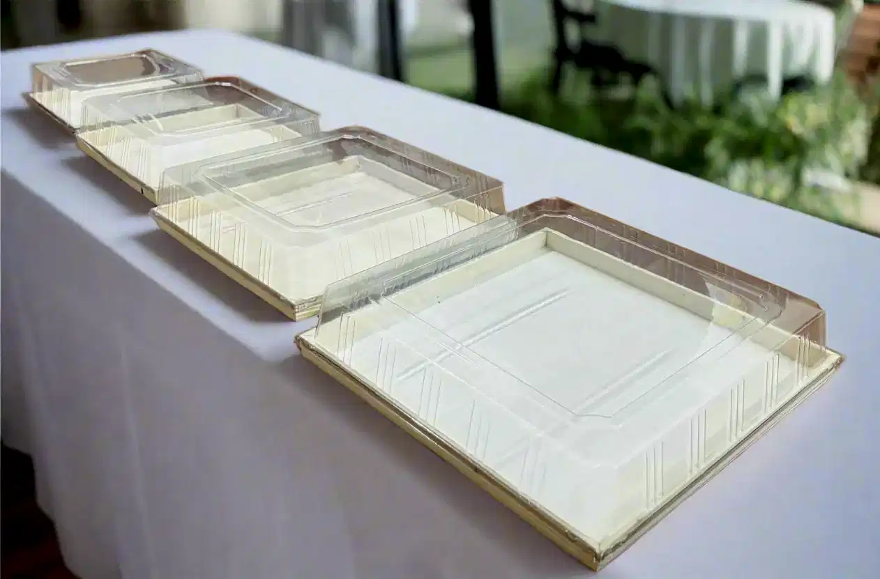 Set of clear plastic trays on a white tablecloth with a blurred outdoor background

